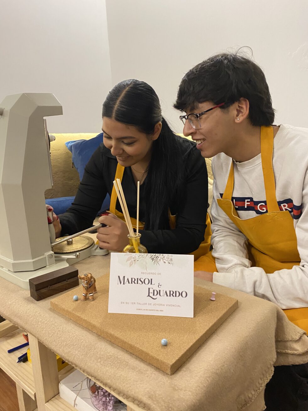 Manos grabando aros de plata sobre una mesa de madera.